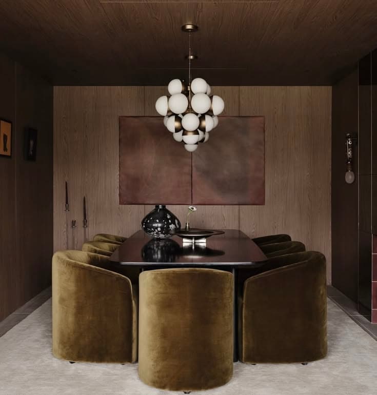 Modern dining room with olive velvet barrel chairs, dark table, and a large globe chandelier.